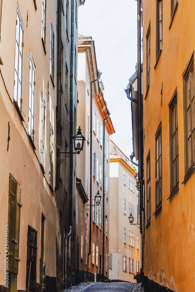 Stockholm narrow street. Orange, yellow houses and street lights. View from below of a cozy narrow medieval street yellow orange red buildings facades in Gamla stan, Old Town of Stockholm, Sweden