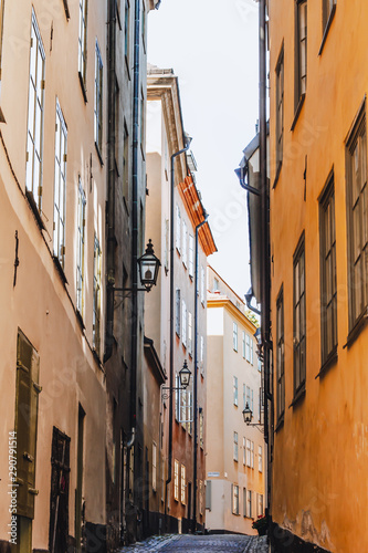 Stockholm narrow street. Orange, yellow houses and street lights. View from below of a cozy narrow medieval street yellow orange red buildings facades in Gamla stan, Old Town of Stockholm, Sweden