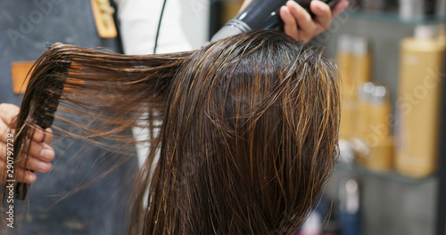 Hair dresser drying woman hair in salon