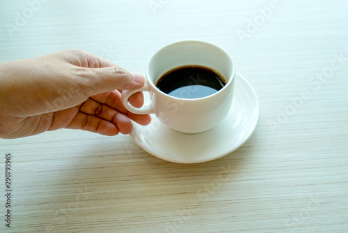 hands holding cups of coffee on wooden table background