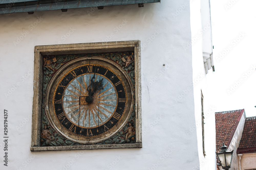 Ancient outdoor clock on white wall in old Tallinn, Estonia Ancient outdoor clock on white wall in old Tallinn, Estonia