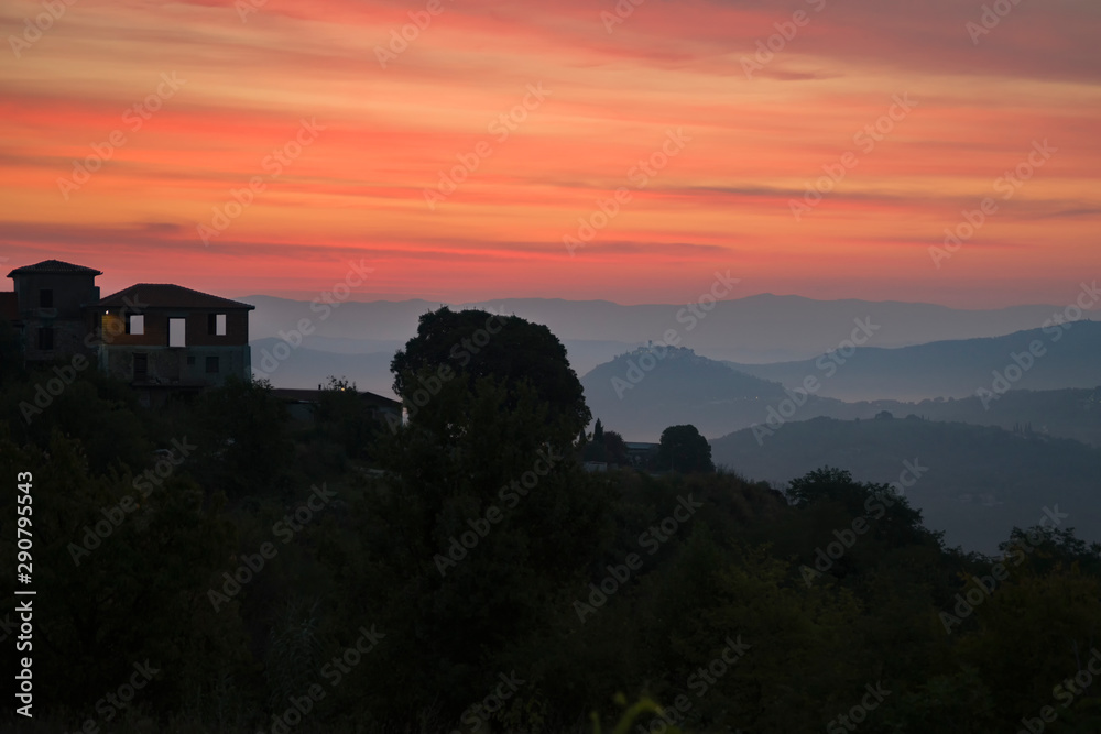 Sunrise over a small village located in the mountains. Depicts a lonely house, mountains, morning mist and Golden-red sky. Copy space. Sunrise over a small village located in the mountains. Depicts a lonely house, mountains, morning mist and Golden-red sky. Copy space.