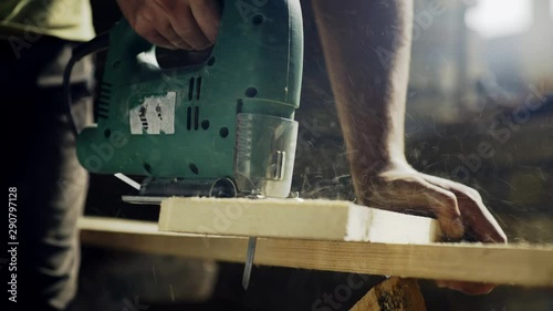 Joiner works with an electric jigsaw and processes wooden products 4K