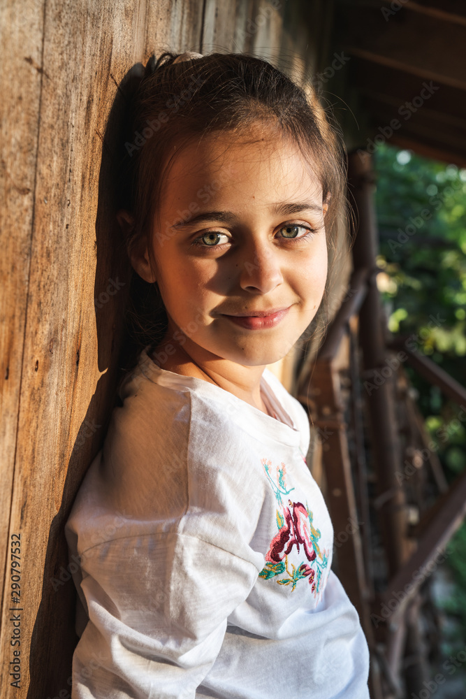 Half length portrait of cute young brunette girl with green eyes that leaned on a wooden wall and looking at the camera with a grin Half length portrait of cute young brunette girl with green eyes that leaned on a wooden wall and looking at the camera with a grin