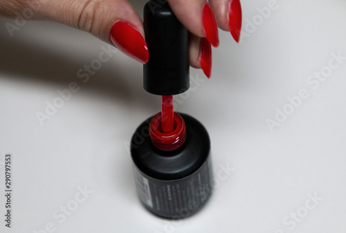 applying red gel nail polish on women's nails