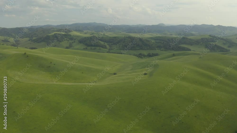 4K resolution, aerial drone at 29 frames per second over mountain in National Park with cloudy skies. Road through the hills.
