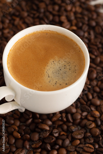 white cup with black coffee and coffee beans close-up