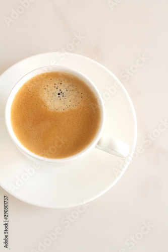 white cup with black coffee on a white background top view