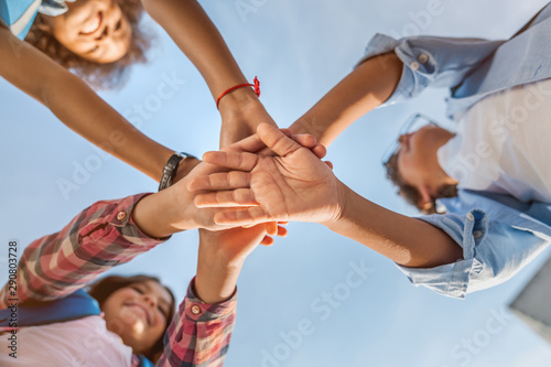 Unity concept. Bottom view of little children putting their hands together indoors