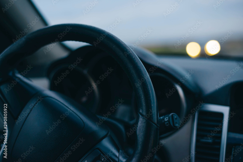 Steering wheel. Oncoming headlights. Sunset. Summer. Travelling by car.
