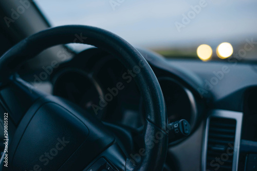 Steering wheel. Oncoming headlights. Sunset. Summer. Travelling by car. © NATALYA