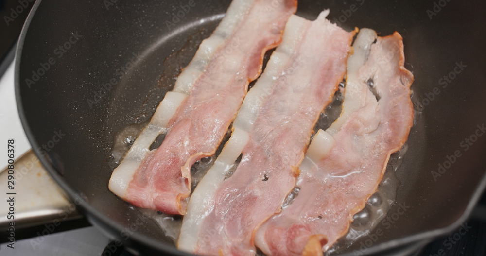 Fry bacon in pan in kitchen for breakfast