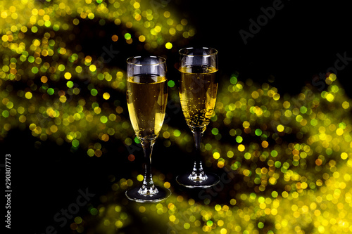 Two clear glasses of champagne filled with sparkling drink on shiny beautiful fesitive sparkling lights bokeh background