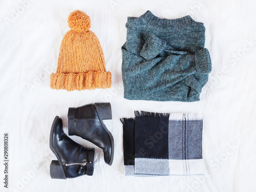 Woman's winter outfit accessories with green woolen sweater, black ankle boots, knitted mustard hat and checked scarf. Flat lay. Top view