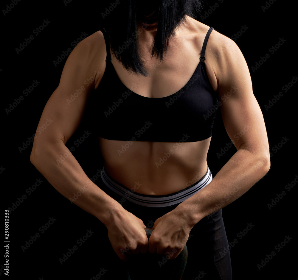 girl of athletic appearance holds an iron kettlebell in front of her girl of athletic appearance holds an iron kettlebell in front of her