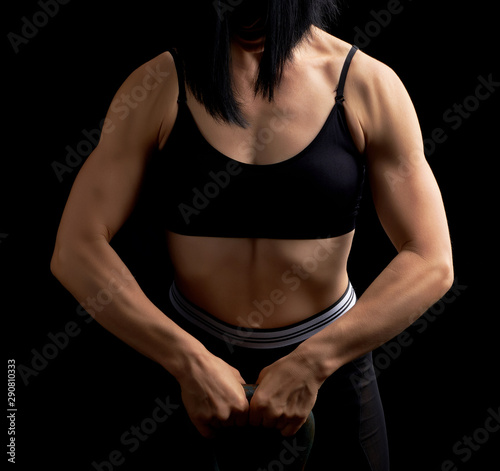 girl of athletic appearance holds an iron kettlebell in front of her