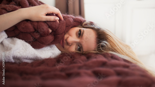 Cute young blonde lying on the bed wrapped in a soft cozy blanket. Warmth and comfort of home photo