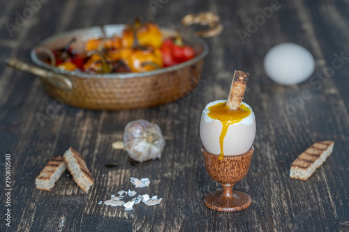 Soft boiled egg in eggcup with slice of toasted bread on wooden table background, closeup