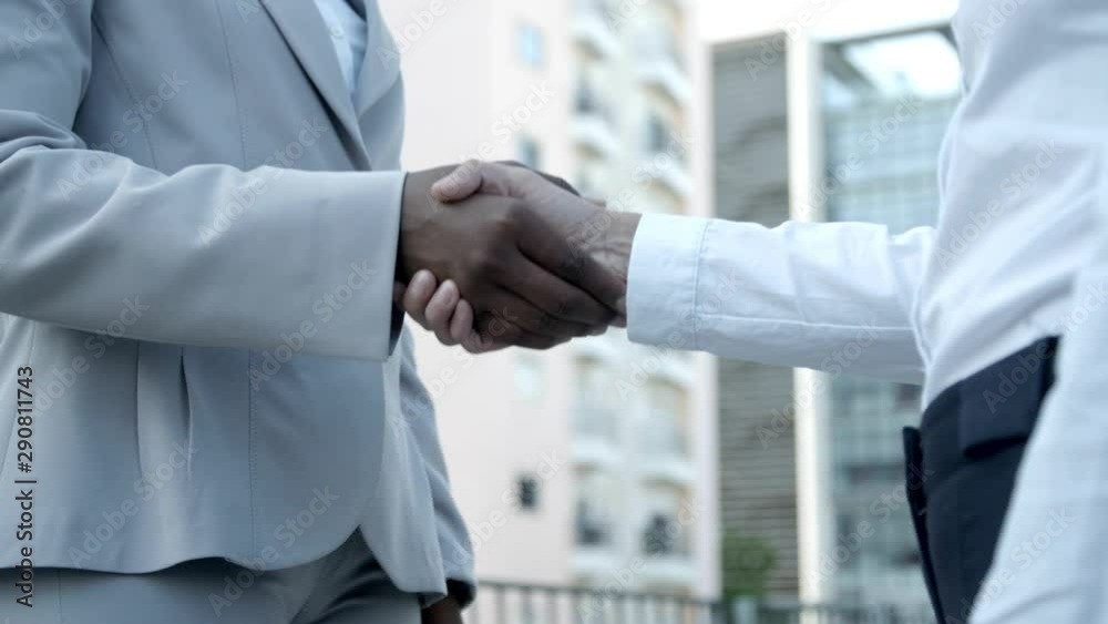 Two employees shaking hands outdoor. Closeup up shot of business people shaking hands. Business handshake concept Two employees shaking hands outdoor. Closeup up shot of business people shaking hands. Business handshake concept