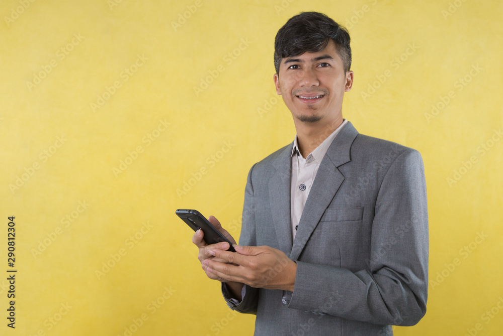 Handsome young Business Asian man using mobile phone isolated on Yellow background.