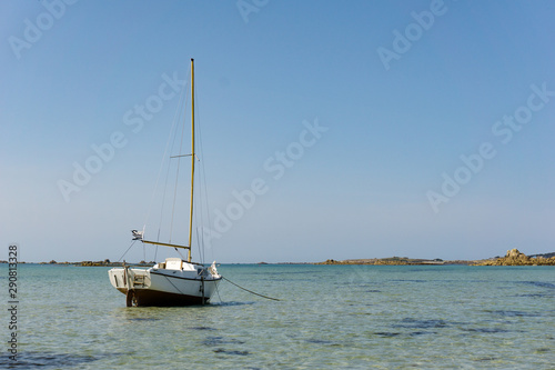horizontal ocean coast and beach landscape with small sailboat under a blue sky