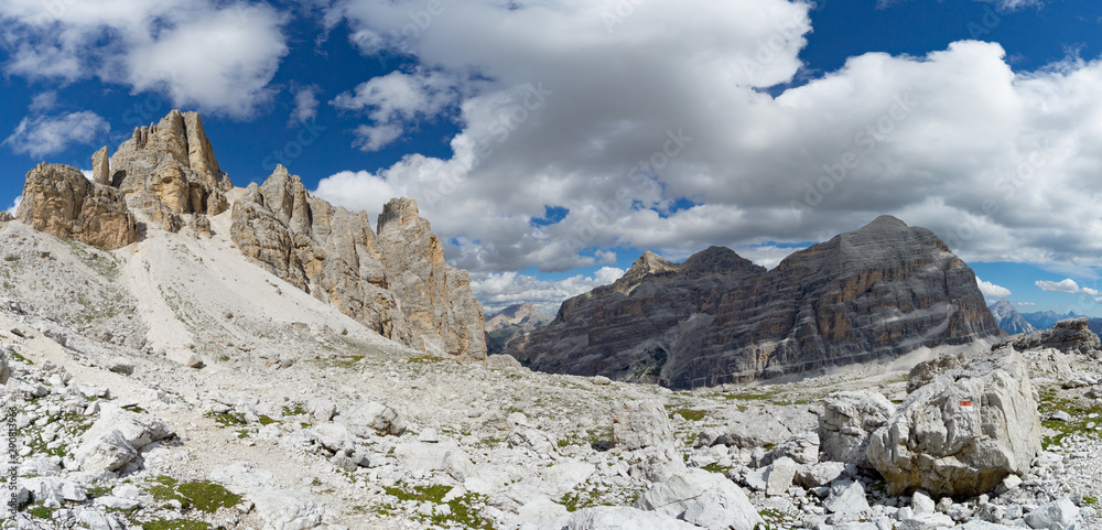 panorama view of wild mountain landscape with rocky peaks and a hiking trail marker and path in the foreground