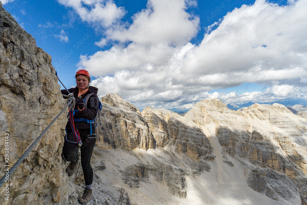 attractive blonde female mountain climber on a steep Via Ferrata in the Italian Dolomites