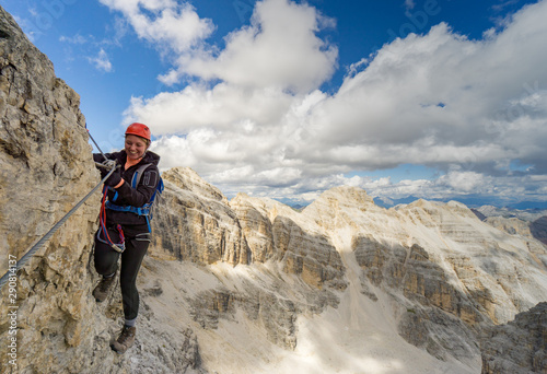 attractive blonde female mountain climber on a steep Via Ferrata in the Italian Dolomites