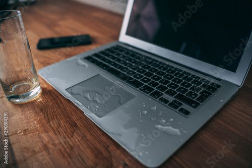 Glass of spilled water on laptop