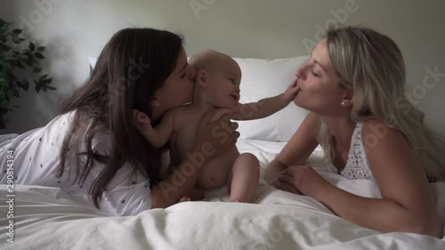 Two lesbian mother and baby on bed having fun