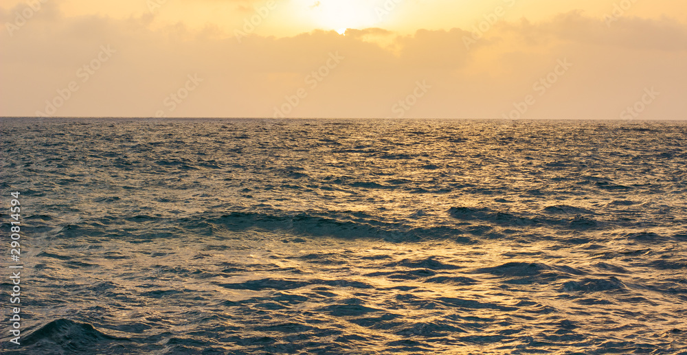 ocean wavy water surface to horizon background idyllic evening sunset scenery landscape poster with empty space for copy or text