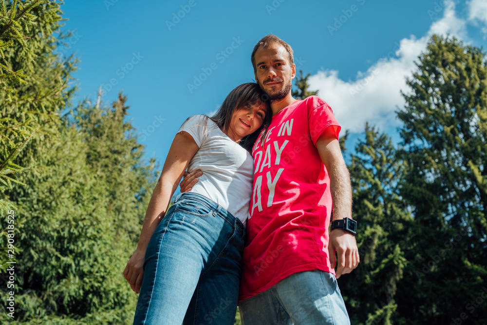 A couple of in love hugs and poses against the background of flowering trees and shrubs. Young guy and girl on the background of a blooming Park
