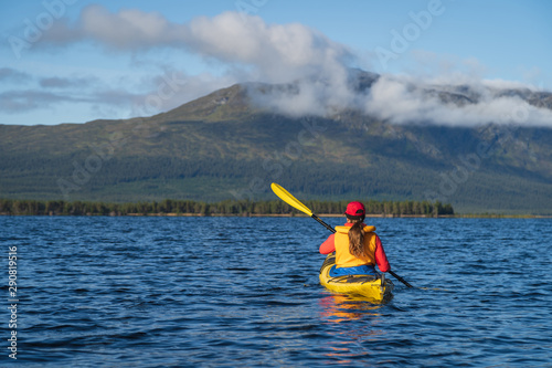 A woman kayaking on a lake in the wilderness. Jamtland, Sweden. © sanderstock