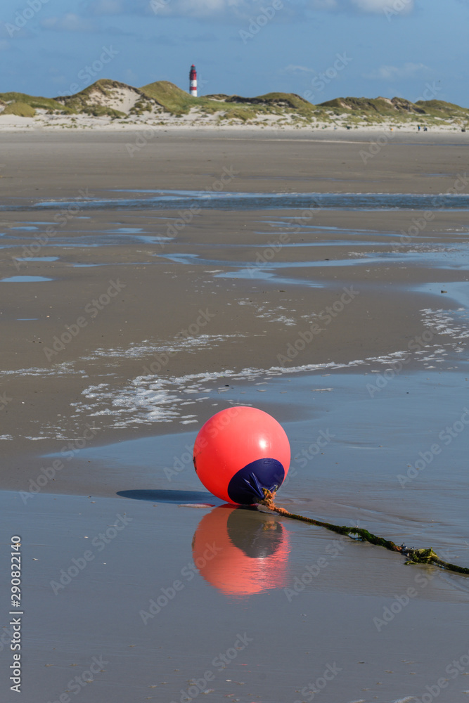 Rote Boje am Strand mit Refelxion vor Dünen und Leuchturm im Hintergrund Rote Boje am Strand mit Refelxion vor Dünen und Leuchturm im Hintergrund