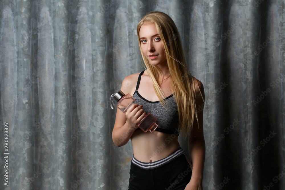Sexy fitness woman. Beautiful athletic girl on the gray background. Fitness sport girl in fashion sportswear doing yoga fitness exercise in the street