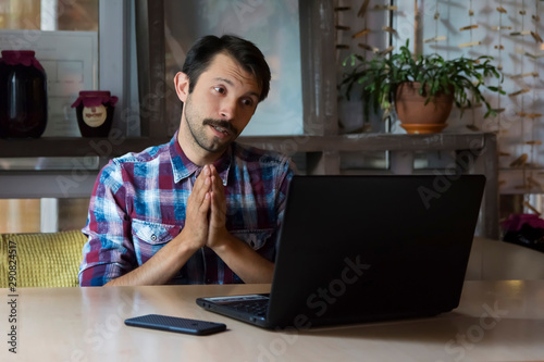 bearded man talking online through the Internet begs his interlocutor photo