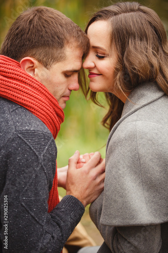 Two lovers in autumn park look on each other with love and tenderness. couple on autumn walk outdoors. Gentle hugs