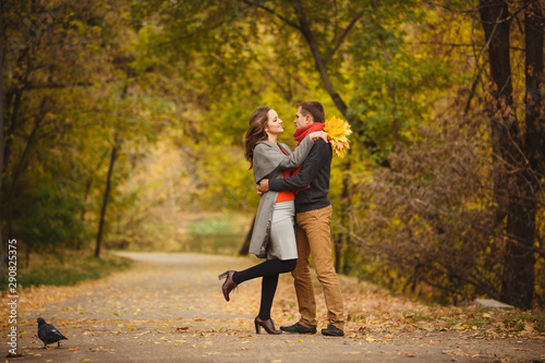 Couple weared in autumn-style clothes (oranfe scarf and vest) running through the autumn landscape. Alley covered with yellow foliage. Autumn walk outdoors. Two lovers in autumn park. Romantic dating © Olga Mishyna