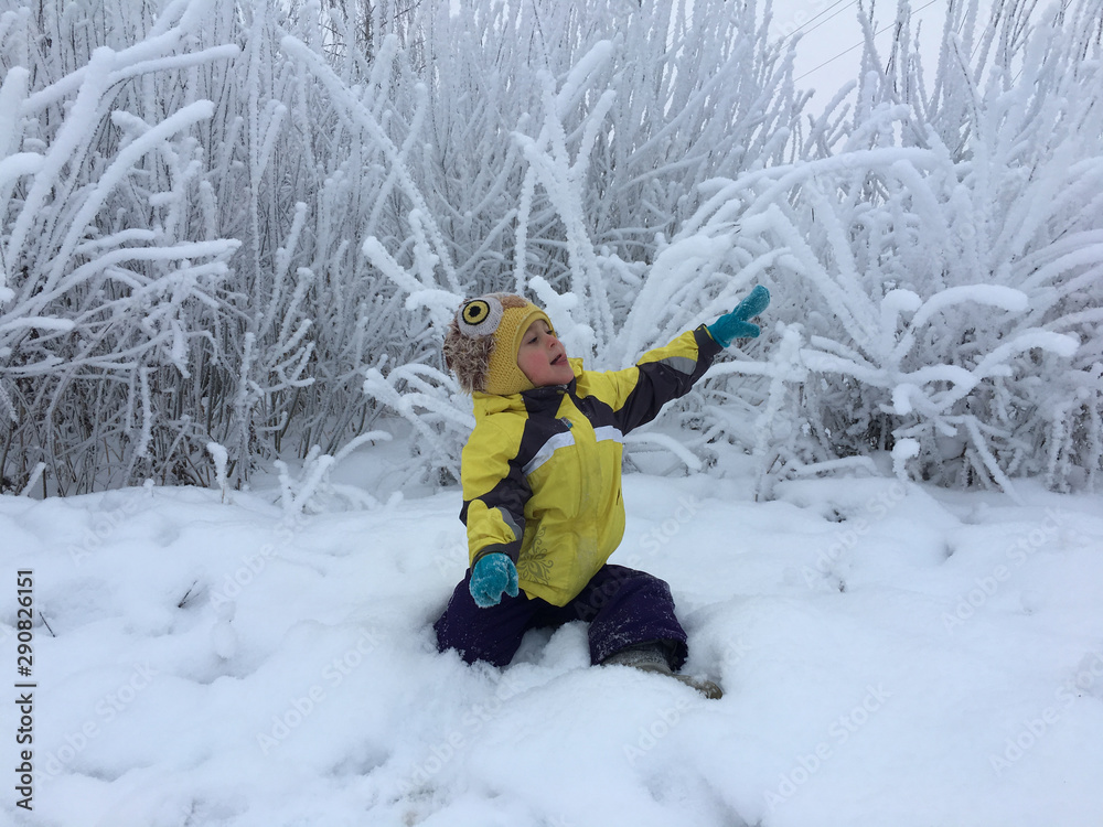 kid reaches up in a snowy forest