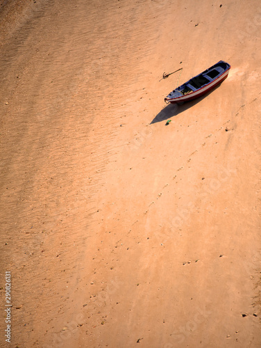 Vista desde arriba de barca de madera de pescadores amarrada en solitario en playa desierta naranja