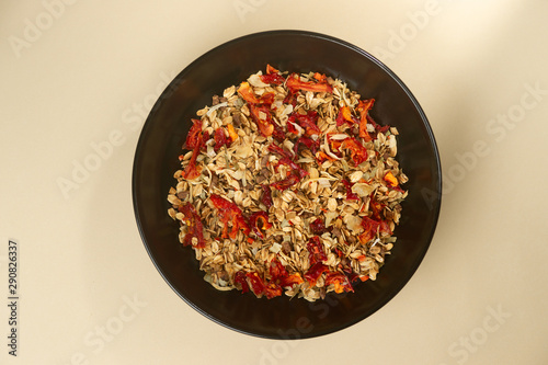 A tasty salt granola with pepper in black bowl on baige bakground. photo