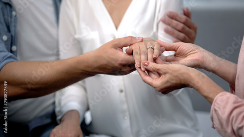 Man holding fiancee hand with engagement ring, showing to mother, happy family