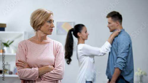 Mother-in-law with hands crossed disapproving young couple relations, loneliness