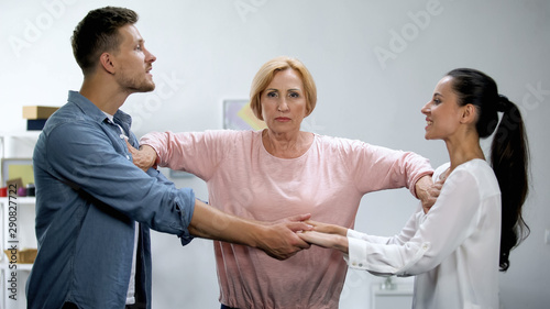 Mother-in-law pushing young man and woman holding hands, interference in family