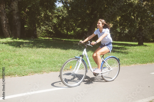 Fototapeta Naklejka Na Ścianę i Meble -  Pretty Young Woman Riding Bicycle In The Park