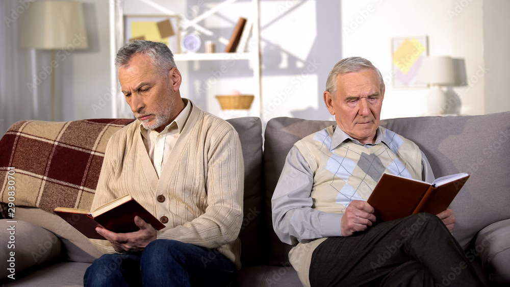Obraz premium Senior men reading books in nursing home sitting sofa, retirement leisure, hobby