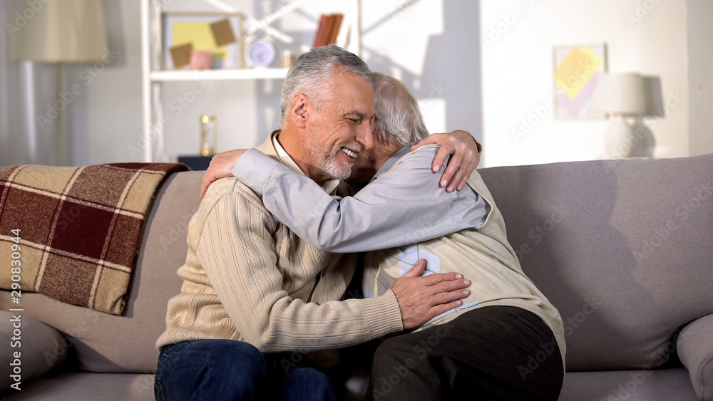 Senior male friends laughing and hugging at home, true old friendship, rest Senior male friends laughing and hugging at home, true old friendship, rest