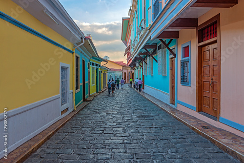 People walking by the colonial style architecture in the most beautiful cobblestone street of Guayaquil at sunset, Santa Ana Hill, Las Penas District, Guayaquil, Ecuador.