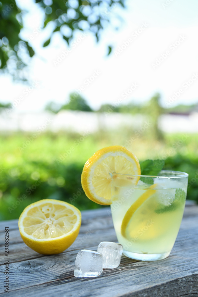 Glasses of lemon juice on a wooden table, summer set, outdoor greed blured background,boke.Water detox Glasses of lemon juice on a wooden table, summer set, outdoor greed blured background,boke.Water detox