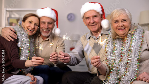 Smiling pensioners holding sparklers looking camera, Christmas celebration
